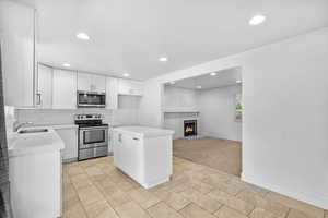 Kitchen with a sink, light countertops, a center island, stainless steel appliances, and recessed lighting