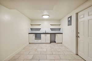 Kitchen with open shelves, a sink, dark countertops, a textured ceiling, and decorative backsplash