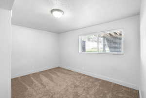 Spare room featuring baseboards, carpet flooring, and a textured ceiling