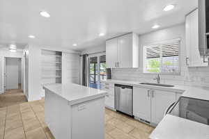 Kitchen featuring a sink, dishwasher, a center island, recessed lighting, and white cabinetry