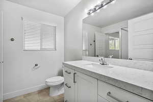 Bathroom featuring tile patterned flooring, vanity, a shower, toilet, and baseboards