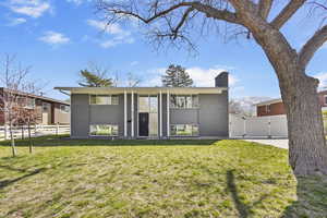 View of front of home with a chimney, fence, brick siding, a front lawn, and a gate