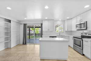Kitchen with a sink, decorative backsplash, appliances with stainless steel finishes, and a kitchen island