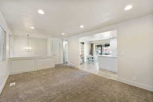 Unfurnished room with baseboards, an inviting chandelier, light carpet, recessed lighting, and visible vents