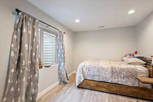 Bedroom with baseboards, recessed lighting, wood finished floors, and visible vents
