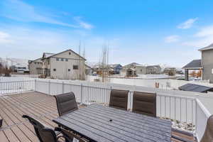Wooden terrace with a residential view, outdoor dining space, and a fenced backyard