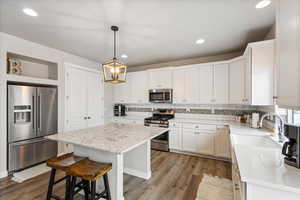 Kitchen with a kitchen island, appliances with stainless steel finishes, tasteful backsplash, a sink, and light wood-style flooring