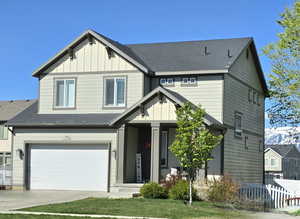 Craftsman house featuring an attached garage, board and batten siding, fence, and driveway