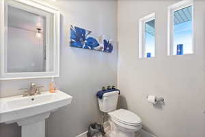 Half bath featuring baseboards, a sink, and toilet
