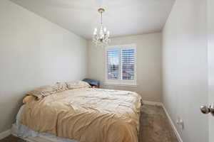 Carpeted bedroom featuring baseboards and a chandelier