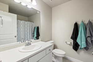 Full bath featuring a shower with curtain, tile patterned floors, baseboards, vanity, and toilet