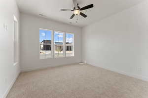 Empty room with baseboards, ceiling fan, visible vents, and light colored carpet