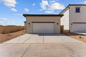 View of front of property with fence, stucco siding, a tiled roof, and a garage