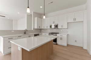 Kitchen featuring visible vents, a center island, a sink, appliances with stainless steel finishes, and backsplash