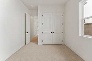 Unfurnished bedroom featuring a closet, carpet flooring, and baseboards