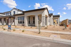 View of front of property featuring stucco siding, a tile roof, stone siding, and covered porch