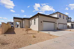 View of front of house with a garage, stucco siding, a tile roof, and concrete driveway