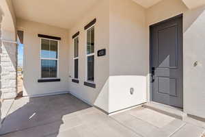 Doorway to property featuring a patio, stucco siding, and stone siding