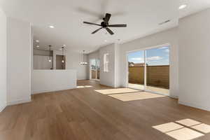 Spare room with visible vents, baseboards, ceiling fan with notable chandelier, light wood finished floors, and recessed lighting