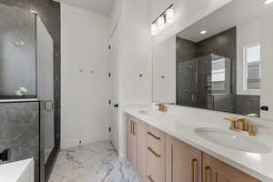 Bathroom featuring double vanity, a sink, marble finish floor, and a stall shower