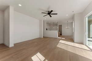 Unfurnished living room featuring visible vents, baseboards, light wood-type flooring, recessed lighting, and ceiling fan with notable chandelier