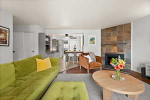 Living area featuring ceiling fan, visible vents, a tiled fireplace, and wood finished floors