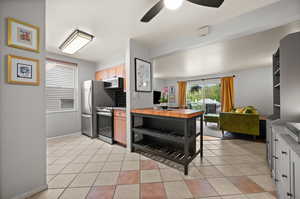 Kitchen featuring ceiling fan, light brown cabinets, stainless steel appliances, baseboards, and light tile patterned floors