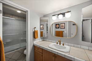 Full bath with a shower with shower door, vanity, toilet, tile patterned floors, and visible vents