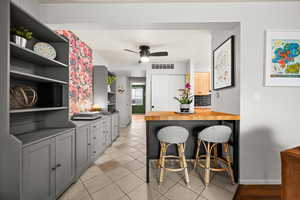 Kitchen featuring light tile patterned flooring, open shelves, ceiling fan, baseboards, and visible vents