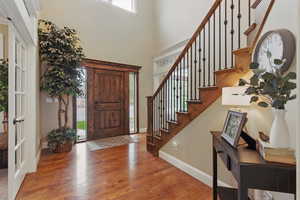 Entrance foyer featuring a healthy amount of sunlight, stairs, and wood finished floors