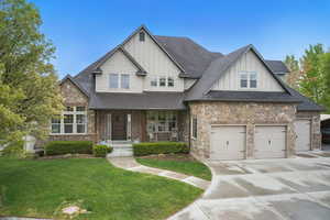 Craftsman-style house with board and batten siding, roof with shingles, a garage, a front lawn, and concrete driveway
