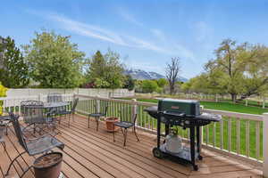Wooden terrace featuring grilling area, a fenced backyard, a mountain view, outdoor dining area, and a yard