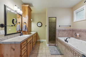 Full bathroom featuring a whirlpool tub, a sink, tile patterned floors, and double vanity