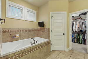 Bathroom with tile patterned floors, a walk in closet, and a garden tub