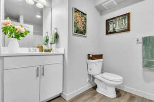 Bathroom with baseboards, wood finished floors, toilet, and vanity