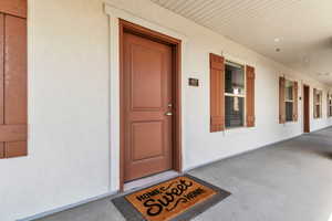 Doorway to property featuring a porch and stucco siding