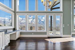 Unfurnished sunroom with french doors, a mountain view, and a chandelier