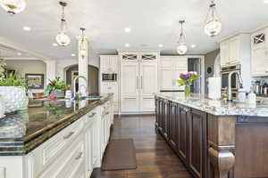 Kitchen featuring arched walkways, appliances with stainless steel finishes, a large island with sink, and a sink