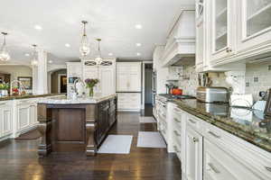 Kitchen featuring a sink, stainless steel gas cooktop, arched walkways, a kitchen island with sink, and recessed lighting