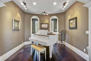 Living area featuring arched walkways, baseboards, rail lighting, and visible vents