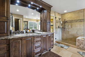 Full bath with double vanity, a sink, a tile shower, and recessed lighting