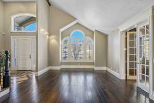 Foyer entrance with baseboards, french doors, hardwood / wood-style flooring, and lofted ceiling