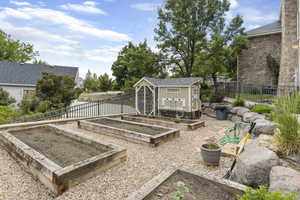 View of yard with fence, an outbuilding, and a vegetable garden
