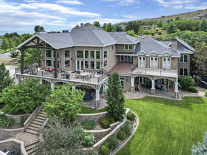 Rear view of property featuring roof with shingles, stairway, a chimney, a patio, and a yard