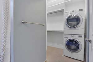 Washroom with laundry area, carpet flooring, baseboards, and stacked washer / dryer