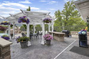 View of patio featuring outdoor dining area, grilling area, fence, and a pergola