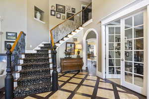 Interior space featuring arched walkways, a high ceiling, baseboards, and french doors