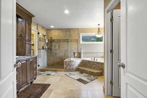 Bathroom with vanity, a textured ceiling, recessed lighting, a bath, and a stall shower