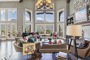 Living area featuring a high ceiling, an inviting chandelier, french doors, and a fireplace