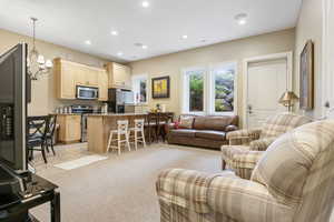 Living area featuring recessed lighting, a notable chandelier, and light carpet